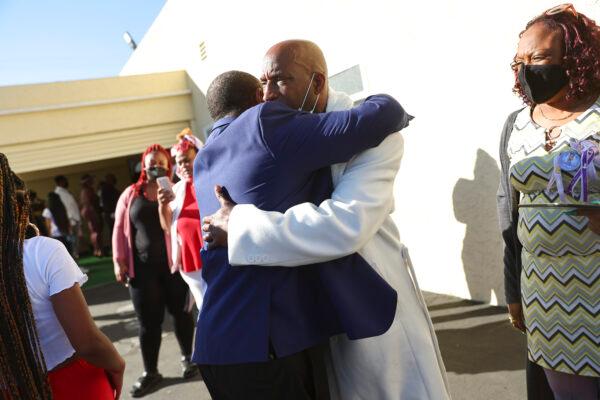 Darius Jackson (C), father of Tioni, is embraced after the funeral for 16-year-old Tioni Theus, whose body was discovered on the side of a freeway in South Los Angeles after she was shot and killed, in Los Angeles on Jan. 27, 2022. (Mario Tama/Getty Images)