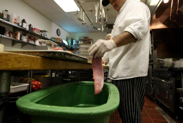 A cook at a restaurant drops food waste into a food scrap recycling container in San Francisco on April 21, 2009. (Justin Sullivan/Getty Images)
