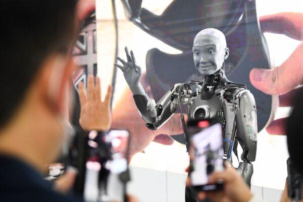 Attendees take pictures and interact with the Engineered Arts Ameca humanoid robot with artificial intelligence as it is demonstrated during the Consumer Electronics Show (CES) in Las Vegas, Nev., on Jan. 5, 2022. (Patrick T. Fallon/AFP via Getty Images)