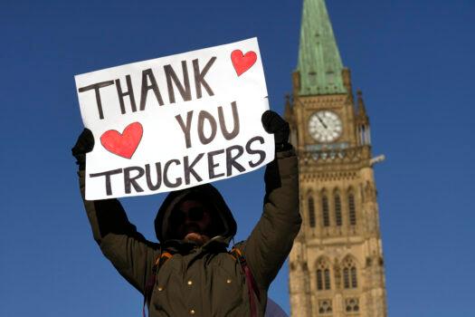 A protester participating in the truck convoy protest against COVID-19 mandates and restrictions holds a sign on Parliament Hill in Ottawa on Jan. 29, 2022. (The Canadian Press/Adrian Wyld)