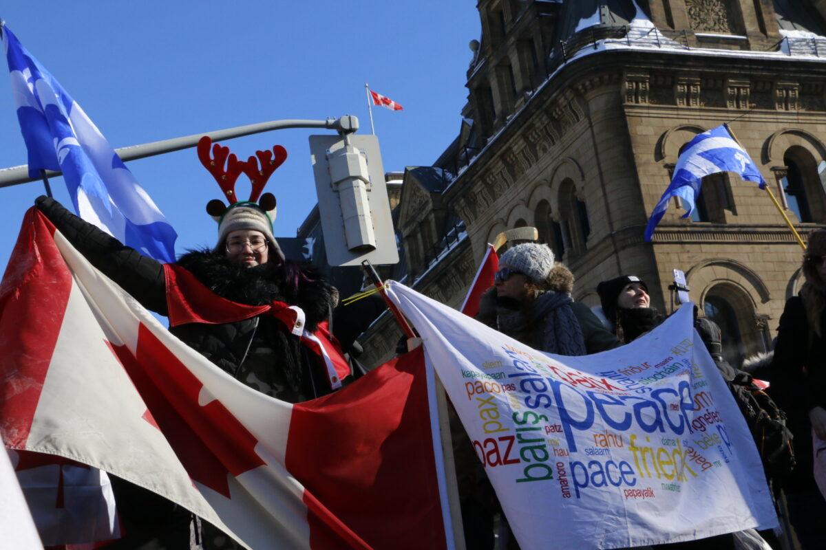 Protesters hold flags and banners in front of Parliament Hill in Ottawa on Jan. 29, 2022. (Noé Chartier/The Epoch Times)