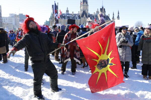 A protester with a Mohawk warrior flag dances on Parliament Hill in Ottawa on Jan. 29, 2022. (Noé Chartier/The Epoch Times)