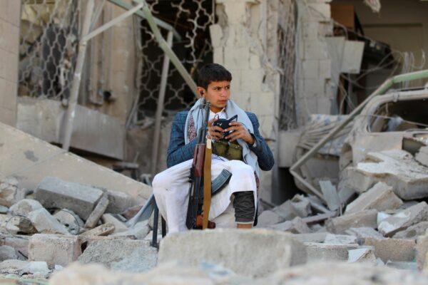 An armed Yemeni youth, loyal to the Shiite Muslim Houthi movement that controls Sanaa, sits amid the rubble on Dec. 5, 2014, guarding the damaged house of the Iranian ambassador in the Yemeni capital, which was targeted by a car bomb earlier in the week. (MOHAMMED HUWAIS/AFP via Getty Images)