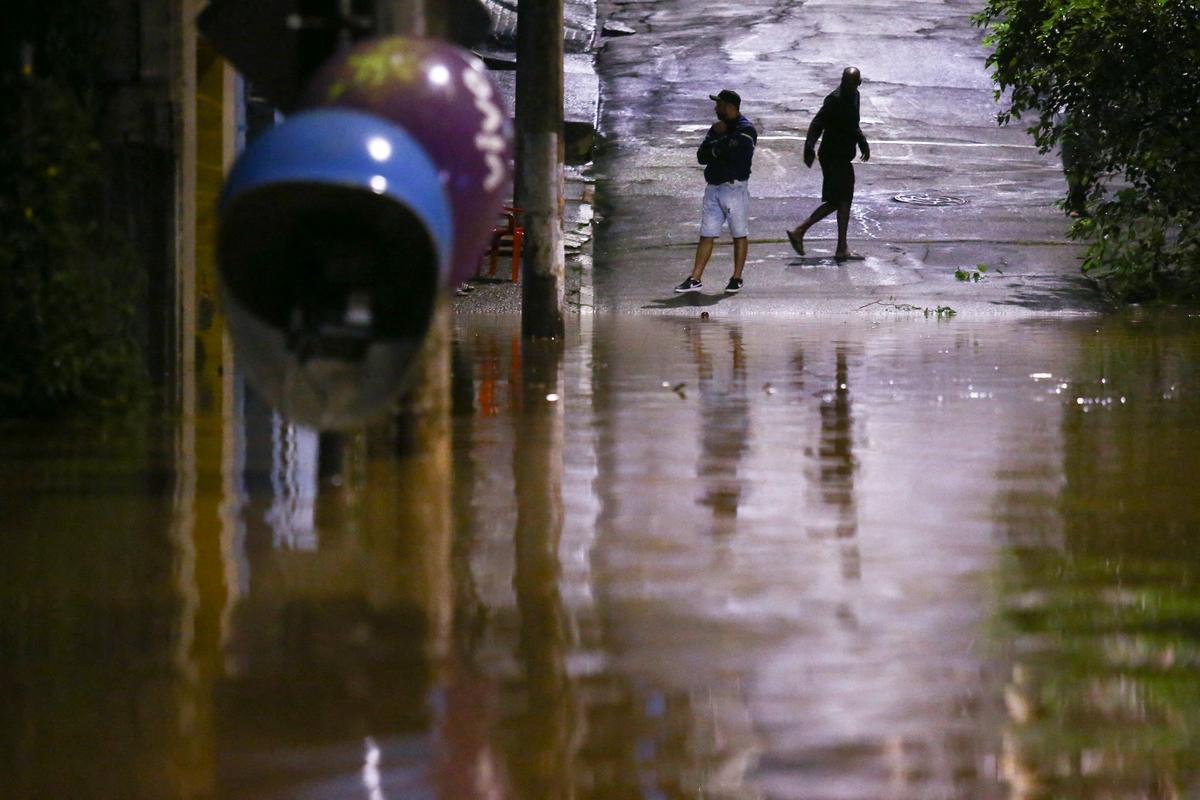 People stand in a flooded street after heavy rain in Caieiras, Brazil, on Jan. 30, 2022. (Carla Carniel/Reuters)