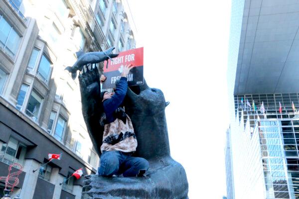  A man gives a bear statue a protest placard in Ottawa on Jan. 29, 2022. (Noé Chartier/The Epoch Times)