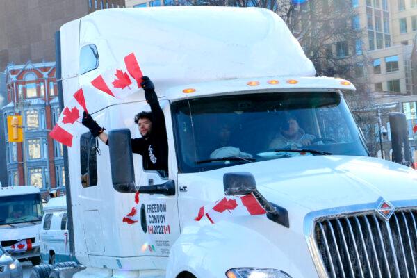  A man waves Canadian flags out of a truck in downtown Ottawa on Jan. 29, 2022. (Noé Chartier/The Epoch Times)
