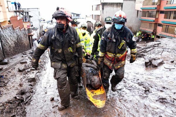 Rescue workers carry away the body of a victim of flash flooding triggered by rain filling up nearby streams that burst their containment mechanisms, collapsing a hillside and bringing waves of mud over homes in La Gasca area of Quito, Ecuador, on Feb. 1, 2022. (Dolores Ochoa/AP Photo)