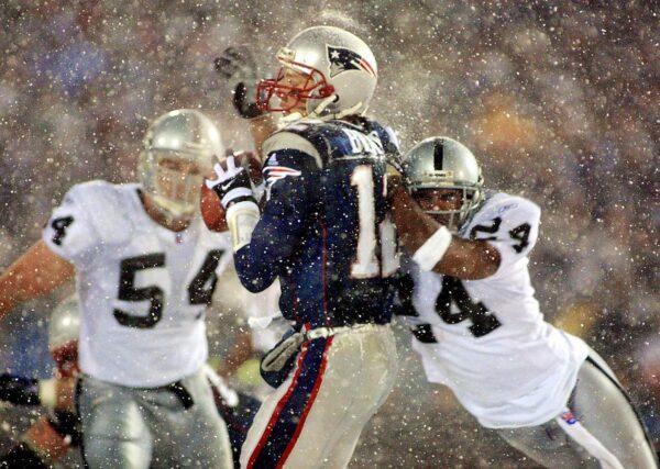 Then-New England Patriots quarterback Tom Brady takes a hit from Charles Woodson (R) of the Oakland Raiders on a pass attempt in the last two minutes of the game in their AFC playoff game in January 2002, now known as the "Tuck Rule Game." (Matt Campbell/AFP/Getty Images)