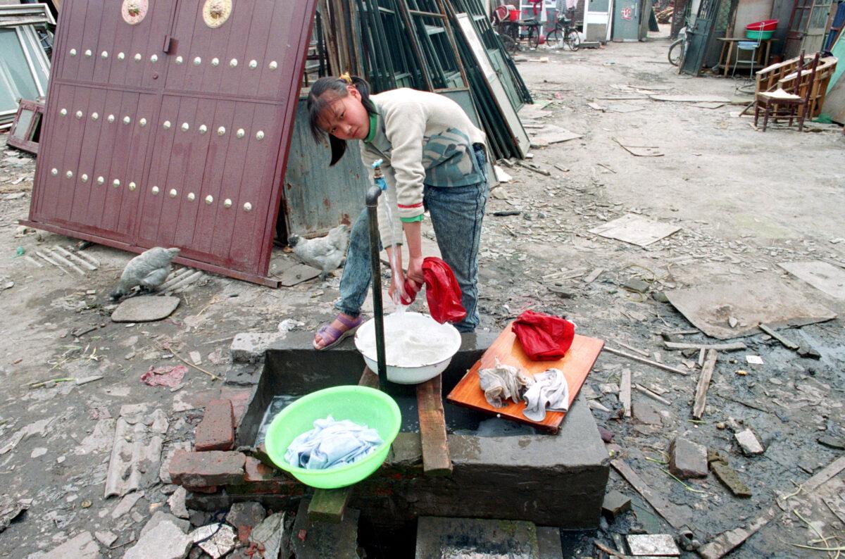 A migrant girl from Henan province does her laundry outside a courtyard shared by several families on May 5, 2003, in Beijing, China.