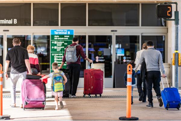 Travelers walk with baggage at John Wayne Airport, in Santa Ana, Calif., on Dec. 30, 2020. (John Fredricks/The Epoch Times)