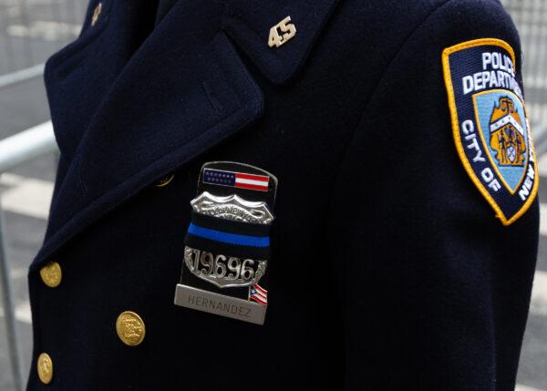 A New York Police Department policewoman wears a mourning band across her shield at St. Patrick’s Cathedral in New York for the funeral of fallen policeman Wilbert Mora on Feb. 2, 2022. (Dave Paone/The Epoch Times)