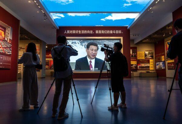 Journalists and others film next to a large screen showing Chinese leader Xi Jinping at the newly built Museum of the Communist Party of China, in Beijing, on June 25, 2021. (Kevin Frayer/Getty Images)