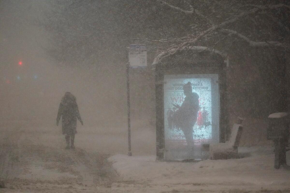 A woman walks to a bus shelter on Dr. Martin Luther King Drive as a man waits in the shelter in Chicago during the pre-dawn hours on Feb. 2, 2022. (Charles Rex Arbogast/AP Photo)