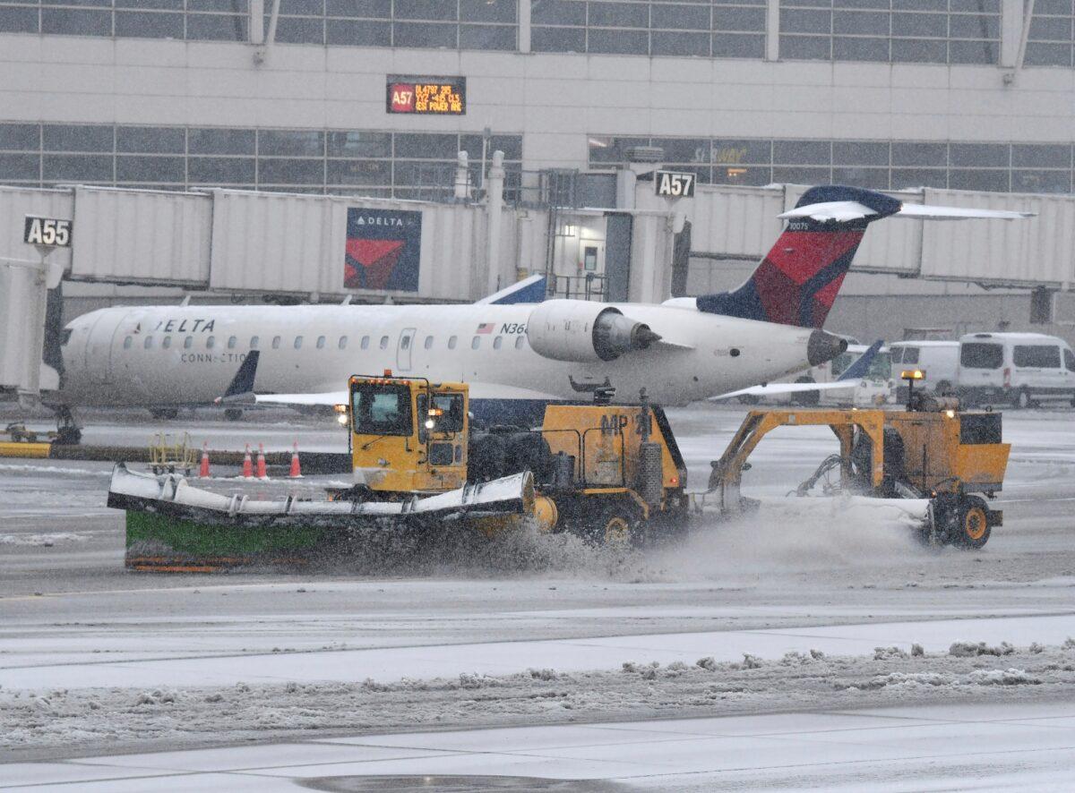 A plow clears away snow on the airport apron at Detroit Metropolitan Wayne County Airport in Romulus, Mich., on Feb. 2, 2022. (Daniel Mears/Detroit News via AP)
