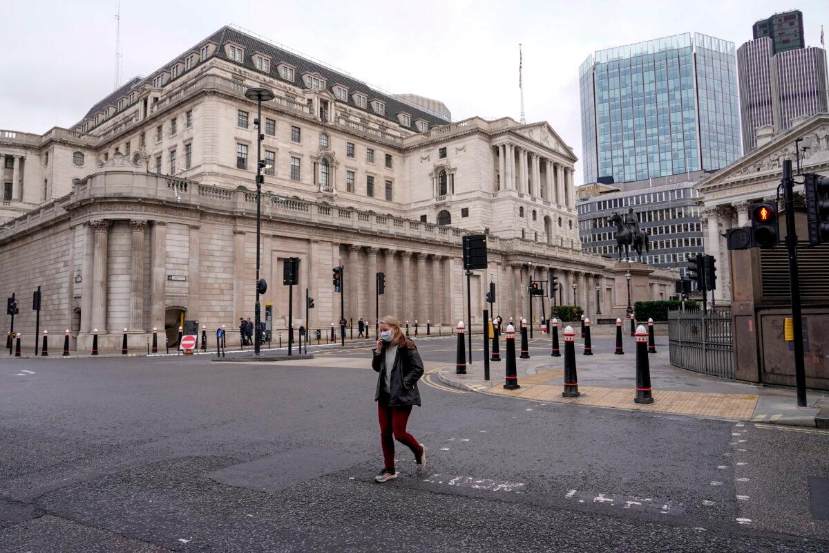 A woman crosses a road outside the Bank of England in London on Dec. 13, 2021. (Alberto Pezzali/AP Photo)