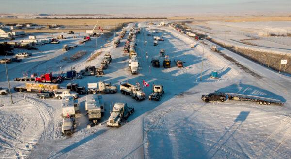Protesters demonstrating against COVID-19 mandates gather as a truck convoy blocks the highway at the U.S. border crossing in Coutts, Alberta, on Feb. 2, 2022. (The Canadian Press/Jeff McIntosh)