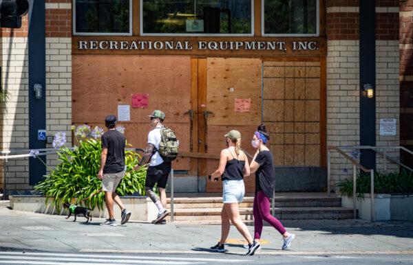 People walk by boarded-up shops destroyed by riots days later in Santa Monica, Calif., on June 6, 2020. (John Fredricks/The Epoch Times)