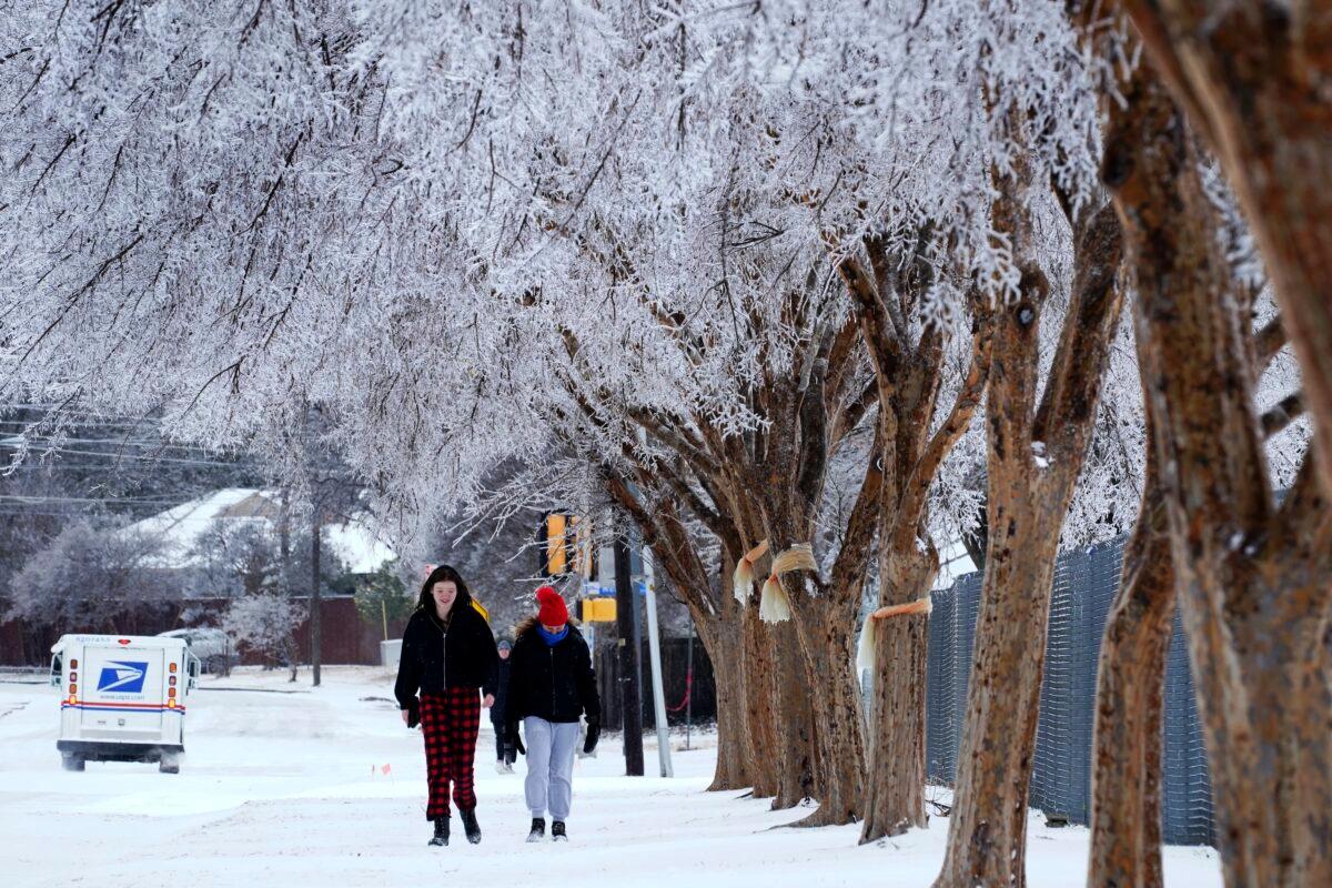People walk on a sidewalk along a busy road where the canopies on the trees were frozen over after a winter storm that moved in overnight in Richardson, Texas, on Feb. 3, 2022. (Tony Gutierrez/AP Photo)
