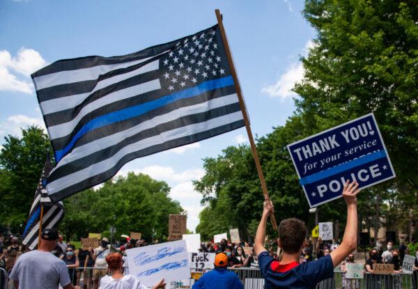 In a file photo, a demonstrator holds a "Thin Blue Line" flag and a sign in support of police during a protest outside the Governor's Mansion in St Paul, Minnesota, on June 27, 2020. (Stephen Maturen/Getty Images)