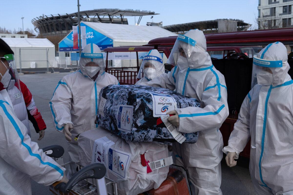 Staff wearing personal protective equipment load luggage belonging to members of Team South Korea onto carts at the Olympic Village ahead of the Beijing 2022 Winter Olympic Games on Jan. 31, 2022. (Carl Court/Getty Images)