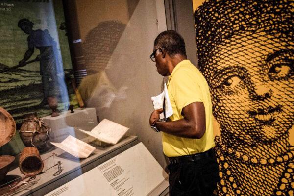 A guest looks at a census and a muster of Virginia, which mentions the first documented African woman to arrive in the colony, at a historical display in Williamsburg, Va., on Aug. 19, 2019. (Brendan Smialowski/AFP via Getty Images)