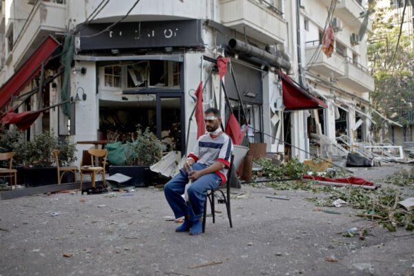 An injured man sits next to a restaurant in the partially destroyed neighbourhood of Mar Mikhael in the aftermath of a massive explosion in Beirut, Lebanon, on Aug. 5, 2020. (Patrick Baz/AFP via Getty Images)