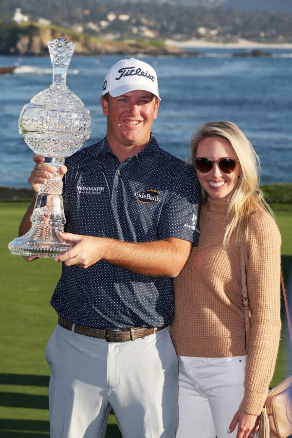 Tom Hoge of the United States celebrates with the trophy and his wife Kelly Hoge after winning during the final round of the AT&T Pebble Beach Pro-Am at Pebble Beach Golf Links, in Pebble Beach, Calif., on Feb. 6, 2022. (Jamie Squire/Getty Images)