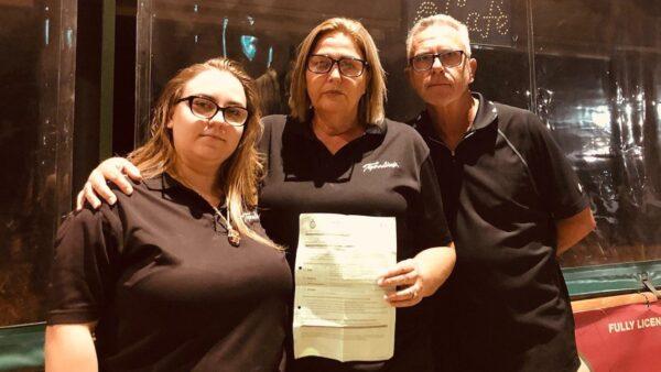 Phil, Jodie, and their daughter holding release papers after being arrested by WA Police outside their Topolinis Caffe restaurant in Perth, Australia on Feb. 7, 2022. (Scorpion Media Group)
