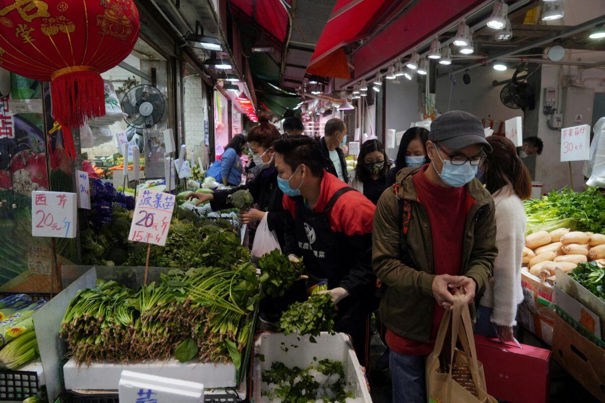 Customers wearing face masks shop for vegetables at a wet market in Tsuen Wan, following the COVID-19 outbreak in Hong Kong, on Feb. 8, 2022. (Lam Yik/Reuters)