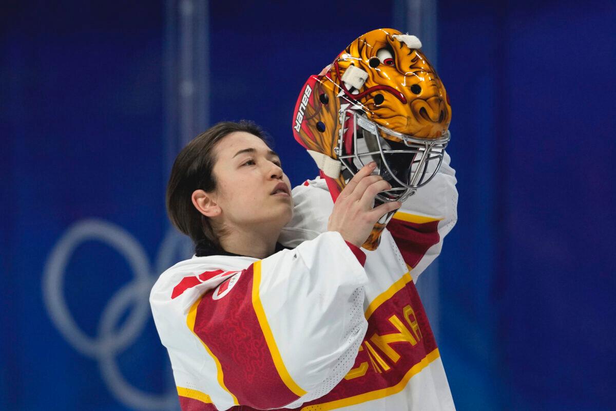 China goalkeeper Zhou Jiaying puts on her helmet during a preliminary round women's ice hockey game against Denmark at the 2022 Winter Olympics, in Beijing, on Feb. 4, 2022. (Petr David Josek/AP Photo)
