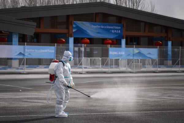 A man in hazmat suit sprays disinfectant against the COVID-19 in a transport hub next to Yanqing that host the alpine skiing and sliding venues ahead of the 2022 Beijing Winter Olympics, on Jan. 31, 2022. (Fabrice Coffrini/AFP via Getty Images)