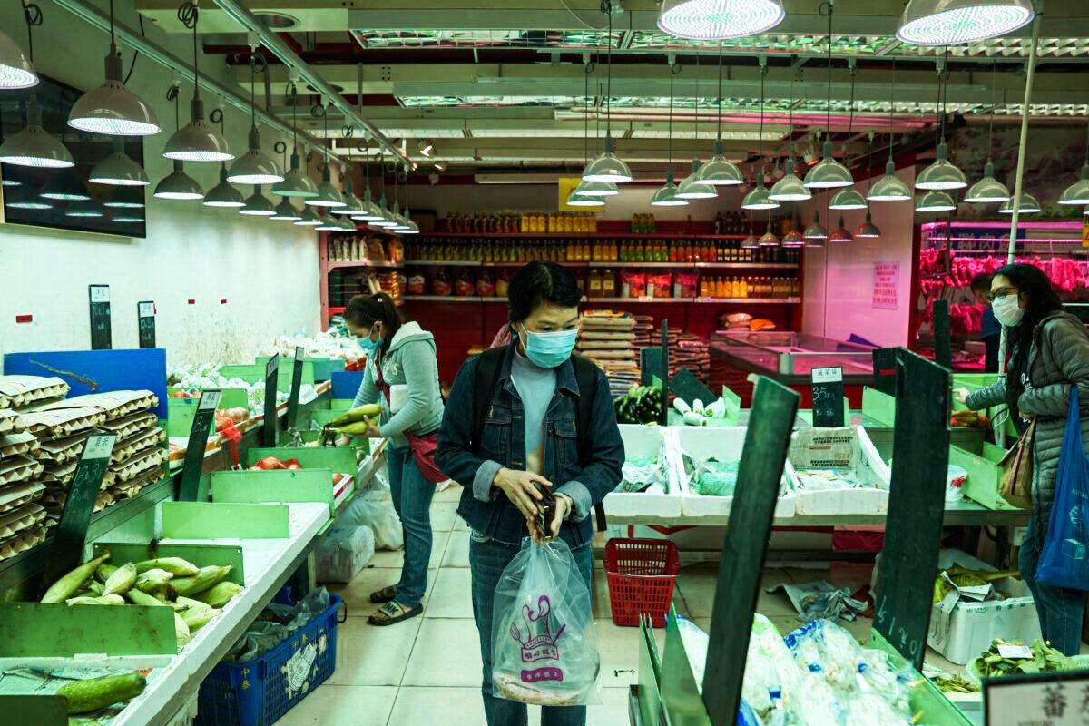 Customers wearing protective masks shop at a market, following the outbreak of COVID-19, at Sha Tin district, in Hong Kong, on Feb. 7, 2022. (Lam Yik/Reuters)