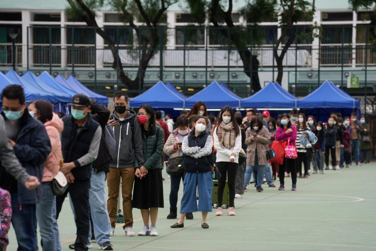 People wearing protective masks and queue at a makeshift nucleic acid testing center for COVID-19, in Tsuen Wan of Hong Kong, on Feb. 8, 2022. (Lam Yik/Reuters)