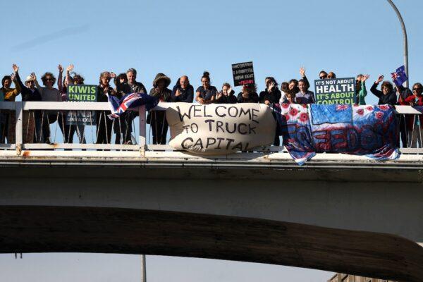 Protesters stand on an overpass to welcome a protest convoy of trucks and other vehicles into central Wellington, New Zealand, on Feb. 8, 2022. (Marty Melville/AFP via Getty Images)