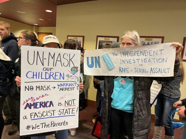 Loudoun County mothers hold up signs against mask mandates before public comment at the Loudoun County School Board meeting in Ashburn, Va., on Feb. 8, 2022. (Terri Wu/The Epoch Times)