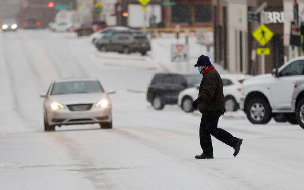  Francisco Savala crosses 15th Street(Cherry Street) between Peoria Ave. and Utica Ave. in the sleet while working at Andolini's Pizzeria in Tulsa, Okla., on Feb. 23, 2022. (Mike Simons/Tulsa World via AP)