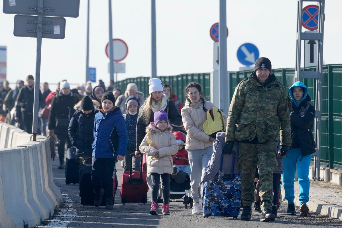 A Polish border guard assists refugees from Ukraine as they arrive in Poland at the Korczowa border crossing, on Feb. 26, 2022. (AP Photo/Czarek Sokolowski)