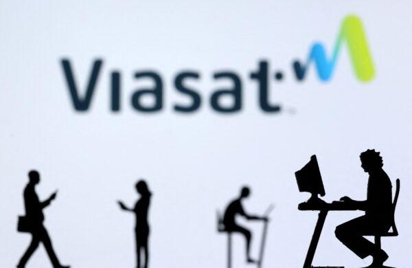 Small toy figures with laptops and smartphones are seen in front of a Viasat Internet logo in this illustration, on Dec. 5, 2021. (Dado Ruvic/Illustration/Reuters)
