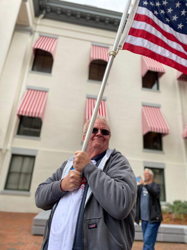 A Convention of States Action team member holds the American Flag during the Rally in Tally on Feb. 8, 2022. (Patricia Tolson/The Epoch Times)
