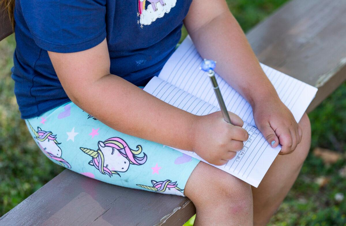 An elementary school student writes in her notebook in Brea, Calif. on May 24, 2021. (John Fredricks/ The Epoch Times)