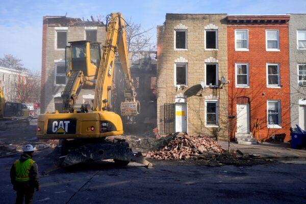 An excavator is used to pull debris off a building during efforts to retrieve the body of a deceased firefighter caught in the building's collapse while battling a two-alarm fire in the vacant row home in Baltimore on Jan. 24, 2022. (Julio Cortez/AP Photo/File)