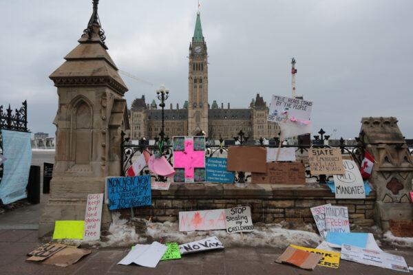 Protest signs adorn a fence around Parliament Hill in central Ottawa on Feb. 11, 2022. (Richard Moore/The Epoch Times)