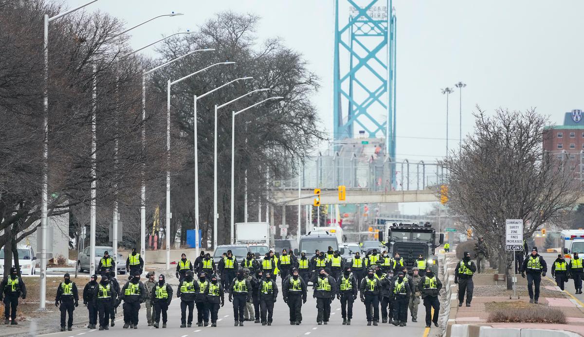 Police walk the line to remove protesters at the Ambassador Bridge, which links Windsor and Detroit, in Windsor on Feb. 13, 2022. (The Canadian Press/Nathan Denette)