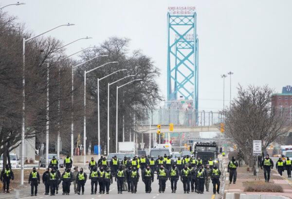 Police walk the line to remove protesters at the Ambassador Bridge, which links Windsor and Detroit, in Windsor on Feb. 13, 2022. (The Canadian Press/Nathan Denette)