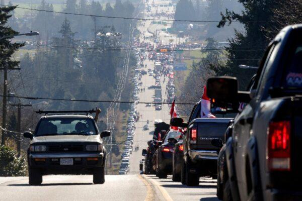 A driver (L) gives a thumbs-up to protesters driving on Highway 15 toward the Pacific Highway Border Crossing in Surrey, B.C., on Feb. 12, 2022. (Jason Redmond/AFP via Getty Images)