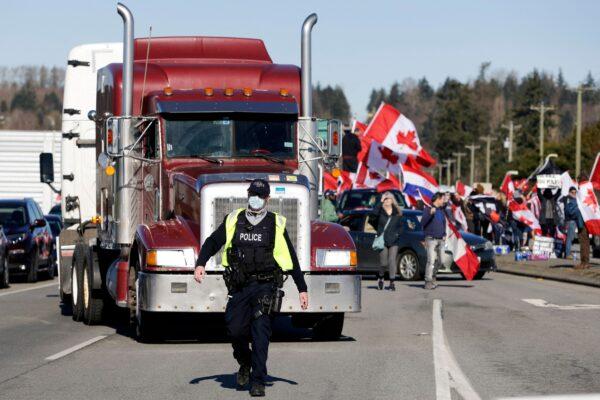 An RCMP officer directs a truck through congestion as protesters demonstrate on Highway 15 near the Pacific Highway Border Crossing in Surrey, B.C., on Feb. 12, 2022. (Jason Redmond/AFP via Getty Images)