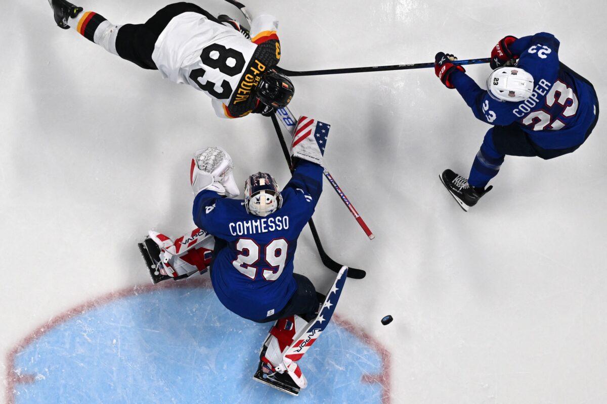 Germany's Leonhard Pfoderl (Top L) challenges USA's goaltender Drew Commesso (Bottom L) and USA's Brian Cooper during the men's preliminary round group A match of the Beijing 2022 Winter Olympic Games ice hockey competition between USA and Germany, at the Wukesong Sports Centre, iin Beijing, on February 13, 2022. (Anthony Wallace/AFP via Getty Images)