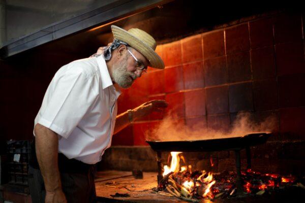 Toni Montoliu cooks a pan of paella over an orange-wood fire. He started helping his mother cook paella at age 5 or 6, then took on the dish by himself around age 16. (Visit Valencía)