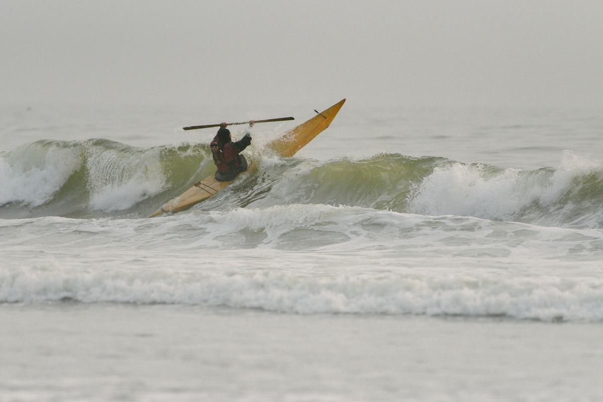 A kayaker crashes through the surf in one of Yuyan's handmade vessels. These kayaks contain no metal hardware, plastic, or vinyl; all of Yuyan's work is bound via traditional knotting methods. (Kiliii Yuyan)