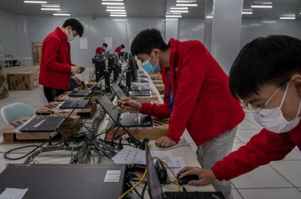 Workers prepare laptops that will be used at venues during an organized media tour and demonstration at the Beijing 2022 Winter Olympic Main Distribution Center (MDC) for equipment and logistics in Beijing, China, on Dec. 9, 2021. (Kevin Frayer/Getty Images)